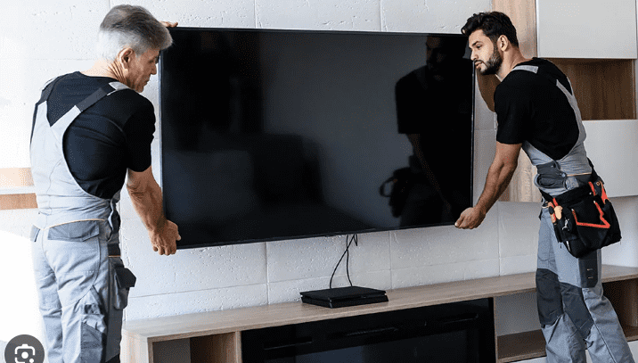 TV installation service technician mounting television on wall at home