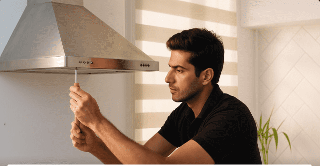 kitchen chimney check-up service technician inspecting chimney motor and filters